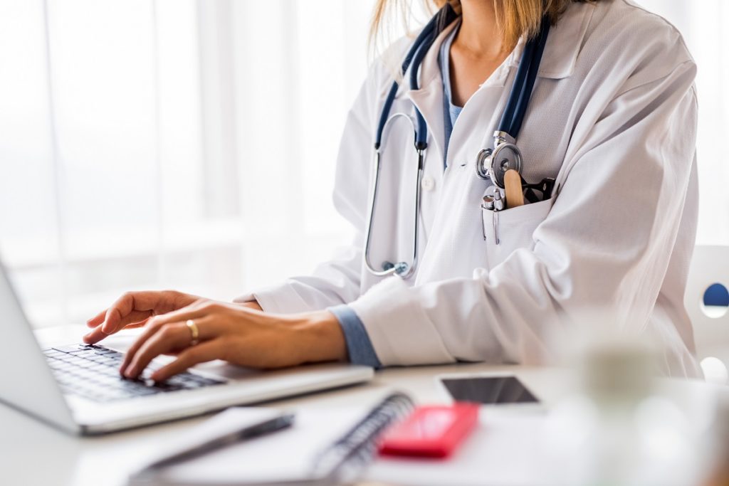 doctor typing on laptop - medical transcription