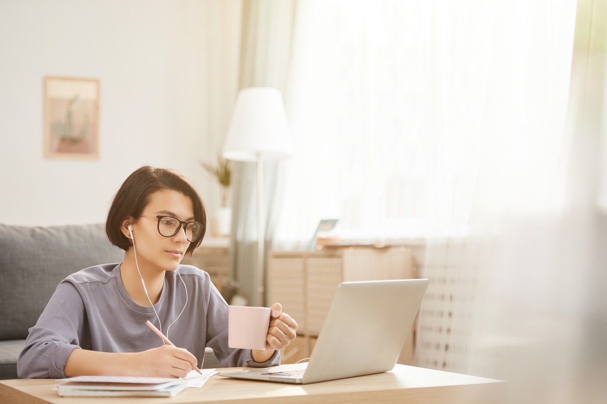 Transcription Services - Woman drinking coffee looking at laptop